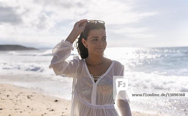 Schöne junge Frau am Strand bei Sonnenuntergang