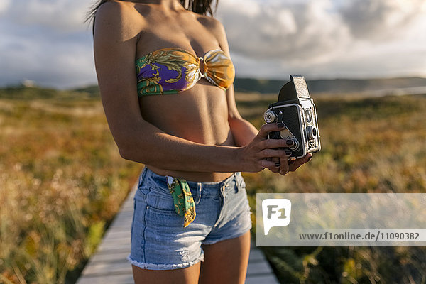 Spanien  Asturien  schöne junge Frau mit klassischer Kamera an der Promenade