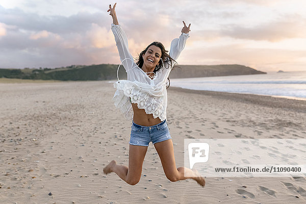 Spain  Asturias  beautiful young woman jumping on the beach