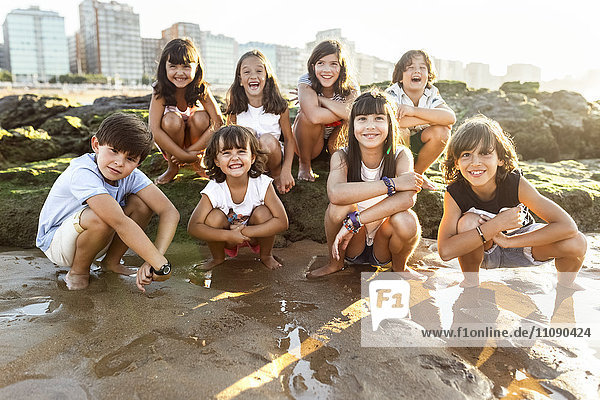 Gruppe glücklicher Kinder am Strand bei Sonnenuntergang