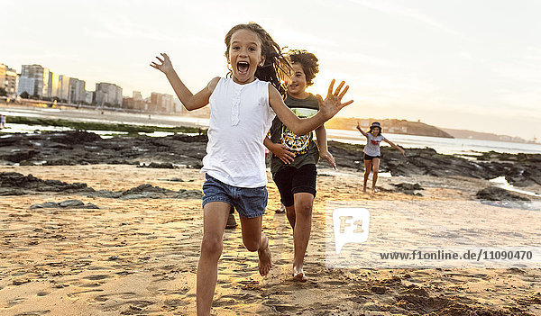 Kinder laufen bei Sonnenuntergang am Strand.