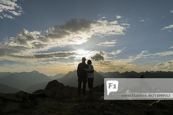 Happy couple watching sunset in the mountains