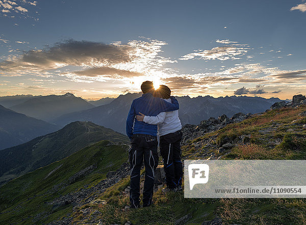 Ein glückliches Paar küsst sich bei Sonnenuntergang in den Bergen.