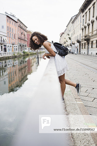 Italien  Mailand  fröhliche junge Frau mit Rucksack am Geländer