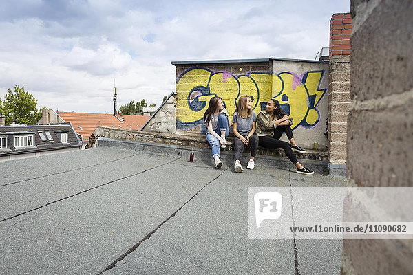 Drei Teenager-Mädchen sitzen zusammen auf dem Dach.