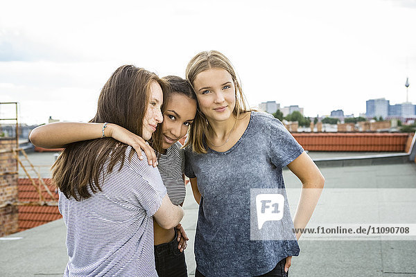 Deutschland  Berlin  drei Teenager-Mädchen stehen Arm in Arm auf dem Dach