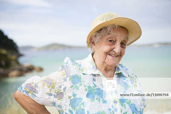 Porträt einer lächelnden Seniorin mit Strohhut