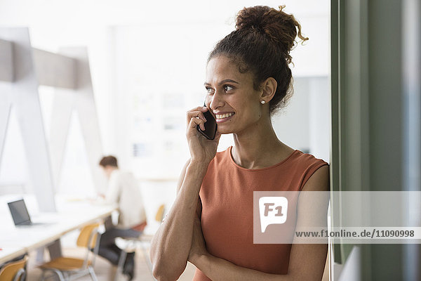 Lächelnde Frau im Büro auf dem Handy