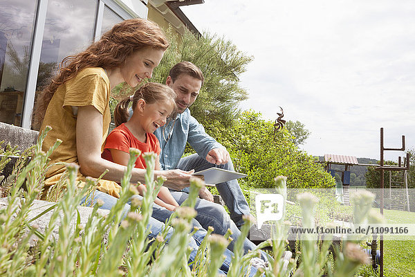 Happy family sitting in garden using tablet