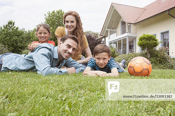 Porträt einer lächelnden Familie im Garten mit Fußball