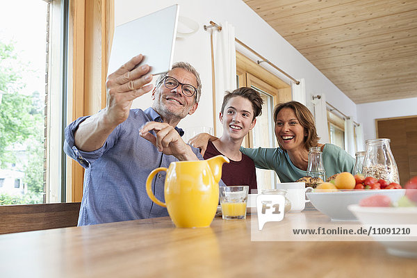 Glückliche Familie  die einen Selfie mit Tablette am Esstisch nimmt