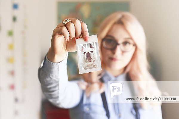 Junge Frau mit einem Polaroid der französischen Bulldogge
