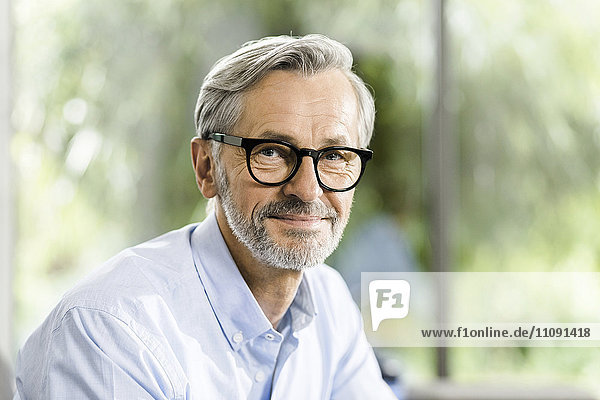 Portrait of smiling man with grey hair and beard wearing spectacles