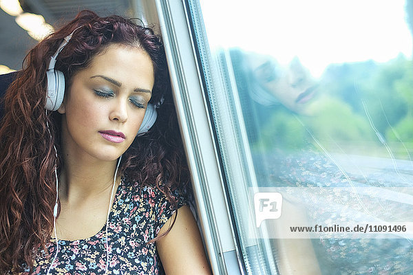 Porträt einer jungen Frau mit Kopfhörer im Zug