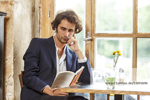 Junger Mann im Café beim Lesen eines Buches