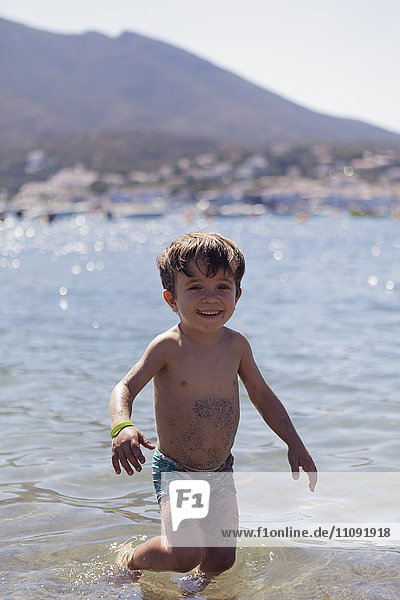 Porträt eines fröhlichen kleinen Jungen  der im Meer watet