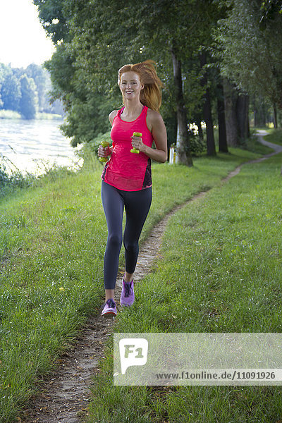 Young woman jogging with dumbbells