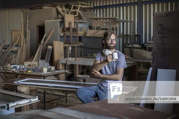 Carpenter drinking coffee in workshop