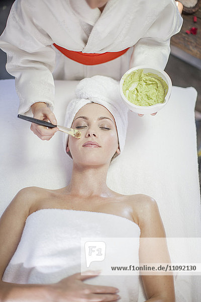 Young woman in spa receiving facial mask