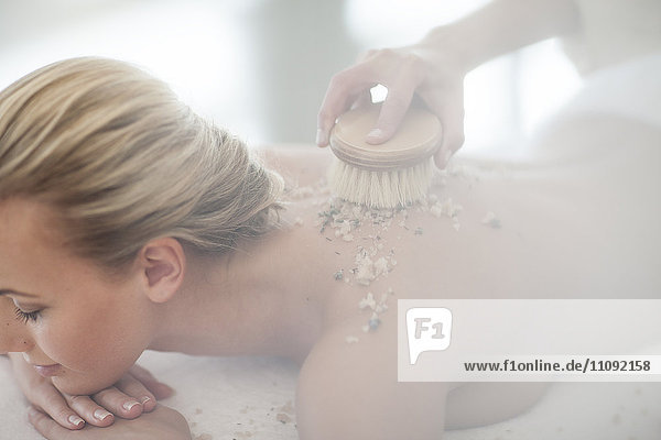 Young woman receiving back peeling at spa