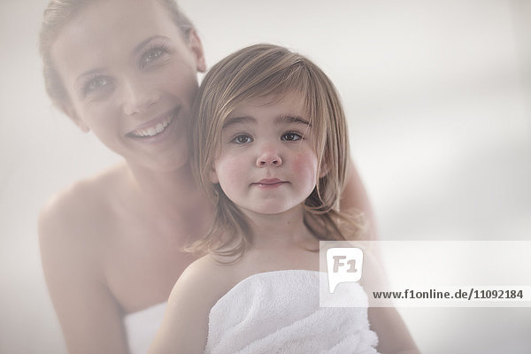 Lächelnde junge Frau und kleines Mädchen in ein Handtuch gewickelt
