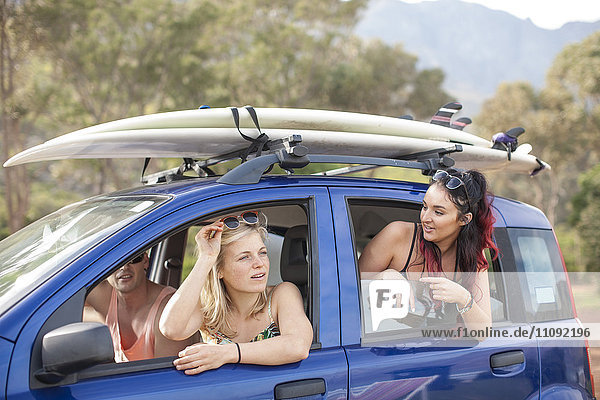Friends omn a trip in car with surfboards on roof