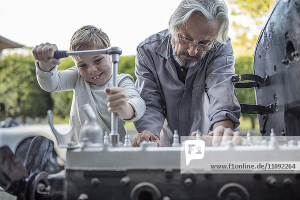Senior Mann und Junge arbeiten an der Mechanik eines Autos