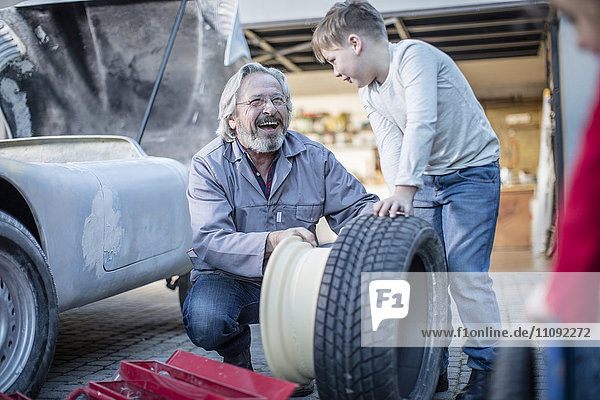 Happy senior man and boy changing car tire