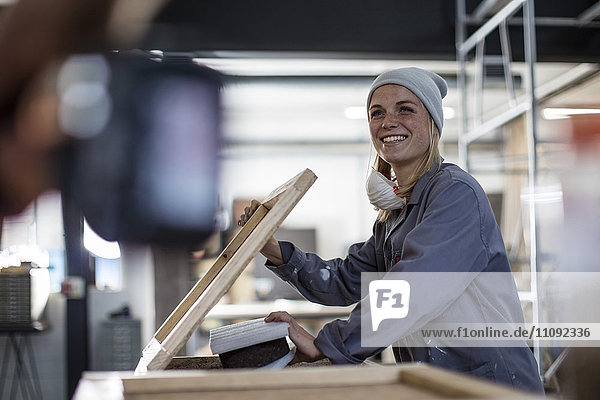 Smiling woman working on frame in workshop