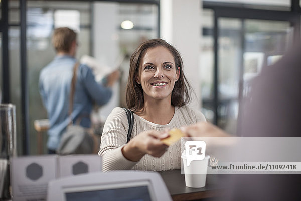 Kunde bezahlt den Kaffee zum Mitnehmen mit Kreditkarte
