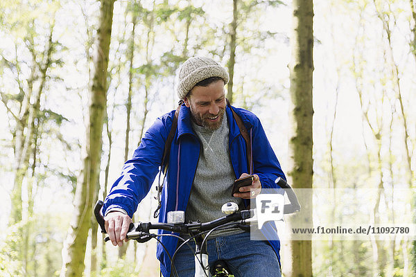 Mann Mountainbike SMS mit Handy im Wald