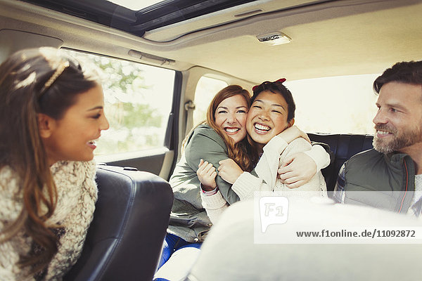 Enthusiastische Freundinnen  die sich auf dem Rücksitz des Autos umarmen.
