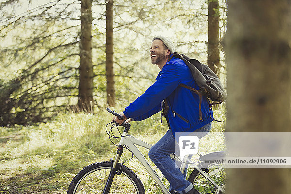 Smiling man riding mountain biking in woods
