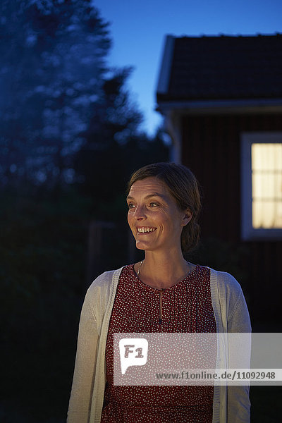 Lächelnde Frau  die im dunklen Hinterhof wegschaut.