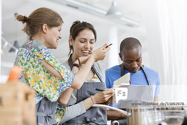 Women tasting food in cooking class kitchen