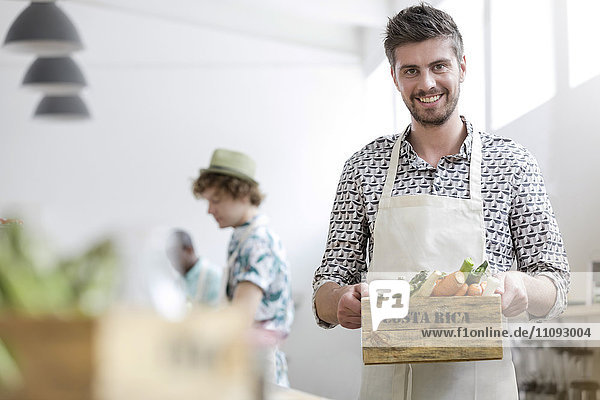 Portrait lächelnder Mann mit frischem Gemüse in der Küche des Kochkurses