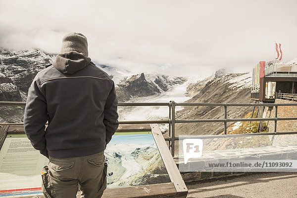 Älterer Mann vergleicht den schmelzenden Großglocknergletscher und den Bach mit einem früheren Bild in einer Vitrine  Gletscher Pasterze  Nationalpark Hohe Tauern  Kärnten  Österreich