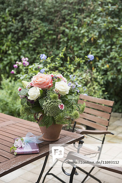 Geschenk mit Blumenstrauß auf Tisch im Garten,  München,  Bayern,  Deutschland