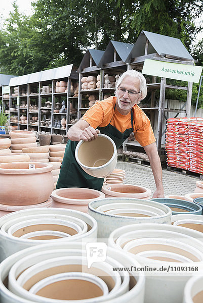 Männlicher Gärtner bei der Untersuchung von Keramiktöpfen im Gewächshaus,  Augsburg,  Bayern,  Deutschland