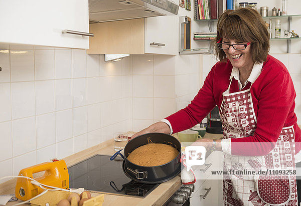 Senior woman preparing cake in kitchen