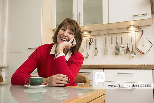 Portrait of a senior woman sitting in the kitchen and smiling