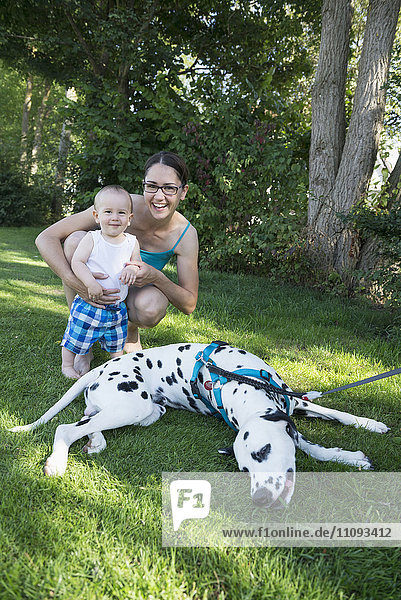 Mutter und kleiner Junge spielen mit Dalmatinerhund auf einer Wiese  München  Bayern  Deutschland