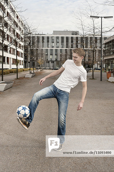 Jugendlicher spielt Fußball  indem er den Ball auf dem Fuß balanciert