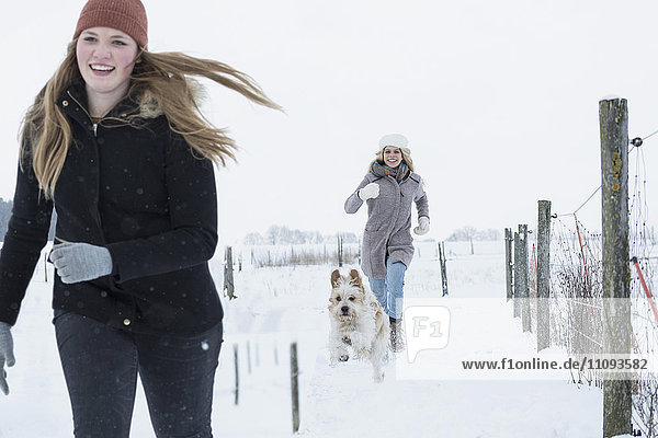 Teenager-Mädchen läuft mit Hund im Schneefeld  Bayern  Deutschland