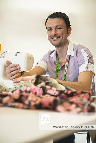 Male dressmaker stitching cloth on sewing machine  Bavaria  Germany