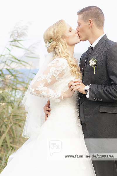 Bride and groom kissing at lakeside
