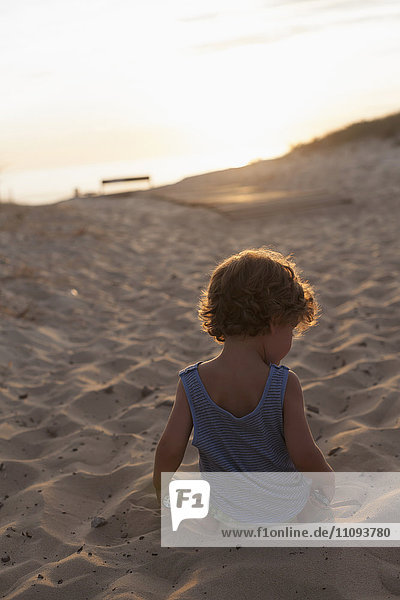 Rückansicht eines Jungen  der bei Sonnenuntergang am Strand spielt