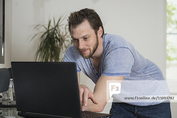 Mid adult man working on laptop in living room,  Munich,  Bavaria,  Germany