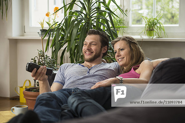 Couple watching television in living room  Munich  Bavaria  Germany