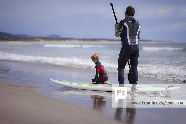 Father with his son paddleboarding on the beach
